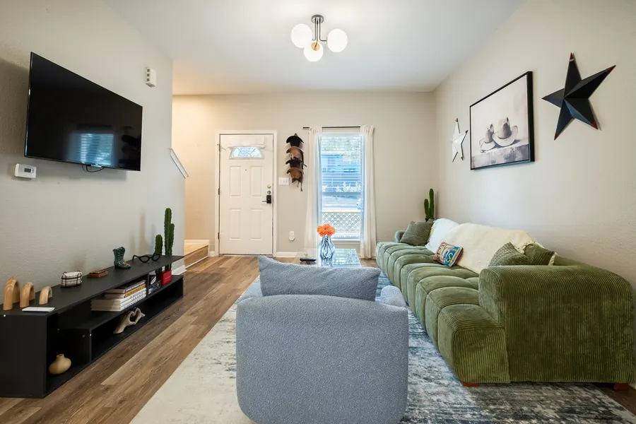 1413 Luna Street living room after grading — green sofa reading true, clean whites at the entry, open sightline to the kitchen.