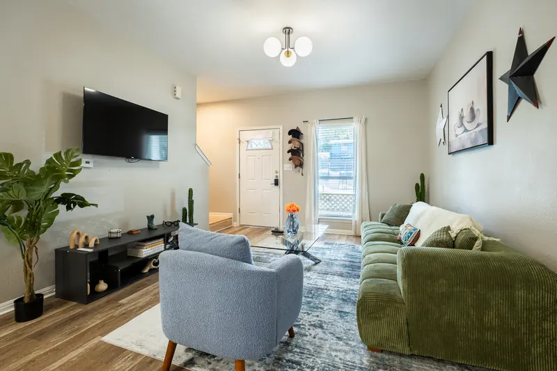 Living room from the sofa side, wall-mounted television above a black console.