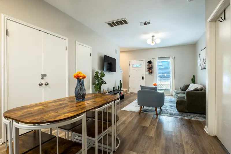 Butcher-block dining table with metal stools, living room beyond.