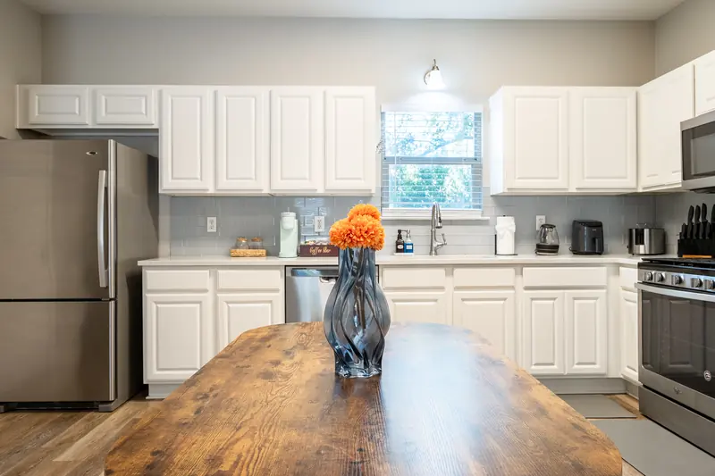 Butcher-block table in the foreground, kitchen run behind it.