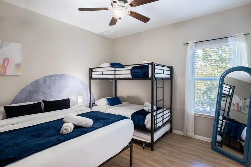 Bunk room with navy bedding, a metal bunk bed and a leaning blue-framed mirror.
