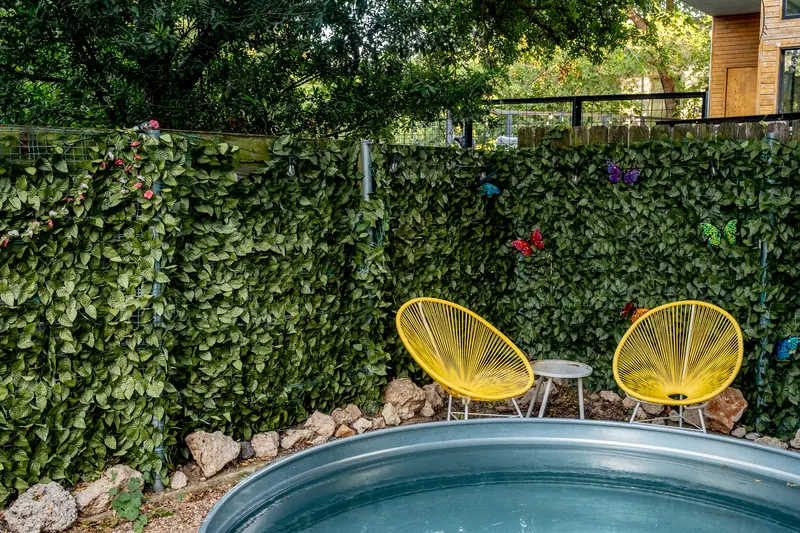 Yard seating beside the pool, gravel and stone border under trees.
