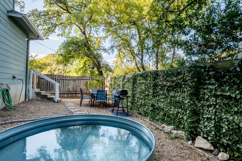Wide view of the backyard with the pool, fence line and neighbouring rooflines.